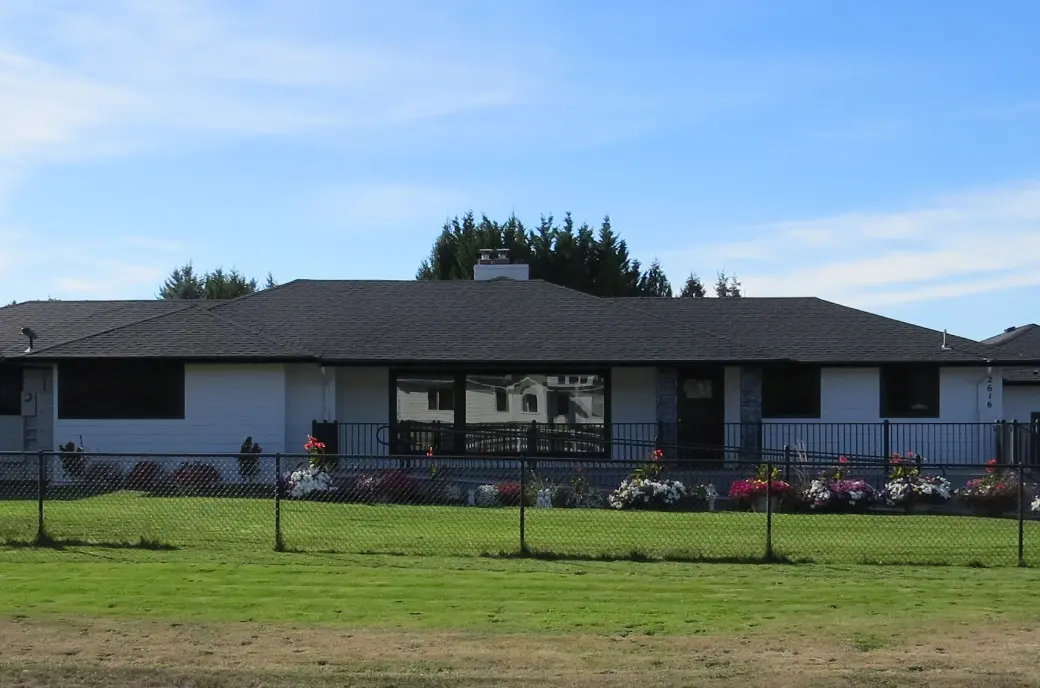 Front of Christina's Place Adult Family Home, a single-story house with a fenced lawn and flower beds