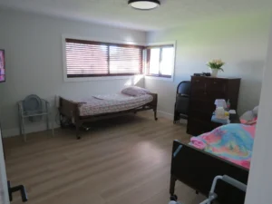 Resident bedroom with a care bed, dresser, and large window