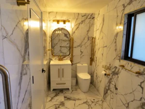 Bathroom with marble-style walls, vanity, and grab bar
